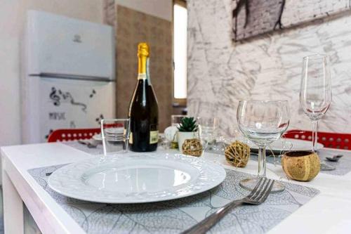 a white plate on a table with a bottle of wine at Appartamento comodo alla metro ideale per coppie e famiglie, casa costa in Collegno