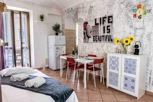 a room with two beds and a kitchen with a table at Appartamento comodo alla metro ideale per coppie e famiglie, casa costa in Collegno