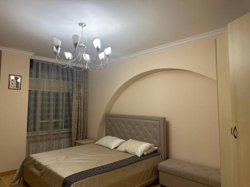 Schlafzimmer mit einem Bett und einem Kronleuchter in der Unterkunft 4-х комнатная квартира in Astana