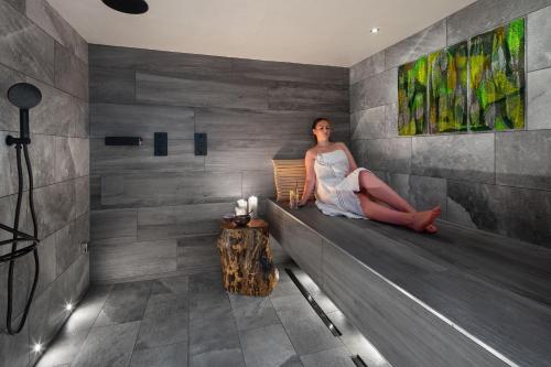 a woman sitting on a bench in a room at Gilpin Hotel & Lake House in Bowness-on-Windermere