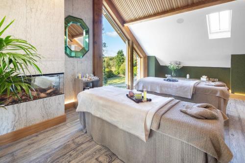 two beds in a room with a fireplace at Gilpin Hotel & Lake House in Bowness-on-Windermere