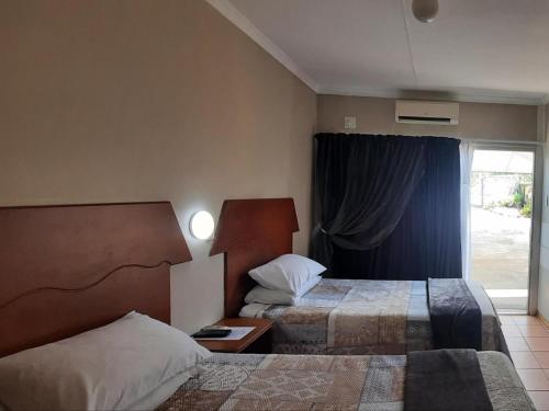 a hotel room with two beds and a window at Kalahari Kaja in Kuruman