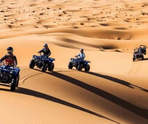 a group of people riding on atvs in the desert at Merzouga nomad style in Merzouga