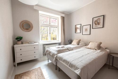 a white bedroom with two beds and a window at 2ndhomes Bright & Spacious, 5 Bedroom Apartment in the Center in Helsinki