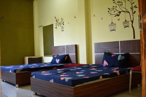 a bedroom with two beds and a tree mural on the wall at HOTEL GS MARRIAGE GARDEN , KARELI in Karelī