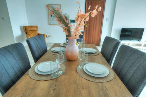 a wooden table with plates and a vase on it at Bright & modern 2bedrooms with sea views GOGZR-2 in Il-Gżira