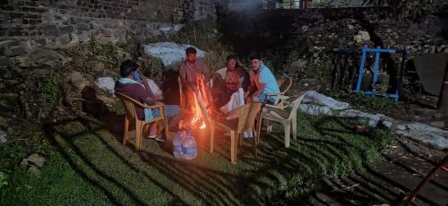 Un gruppo di persone sedute intorno al fuoco di Sugan Residency a Kodaikānāl