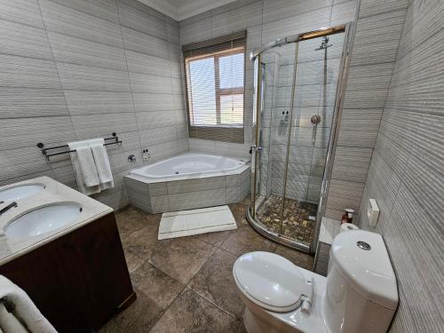 a bathroom with a tub and a toilet and a shower at Leopard Corner Lodge in St Lucia