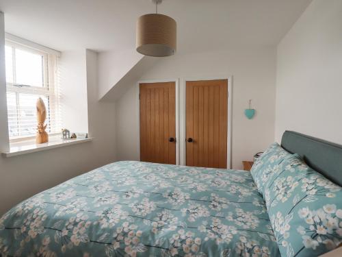 a bedroom with a bed with a blue comforter at Charlotte's Cottage in Seahouses