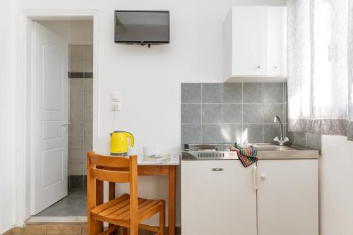 a kitchen with white cabinets and a table with a chair at Livadia Studio A Paros in Parikia
