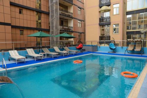Emmad Furnished Hotel في أديس أبابا: مسبح فيه كراسي ومظلات في مبنى