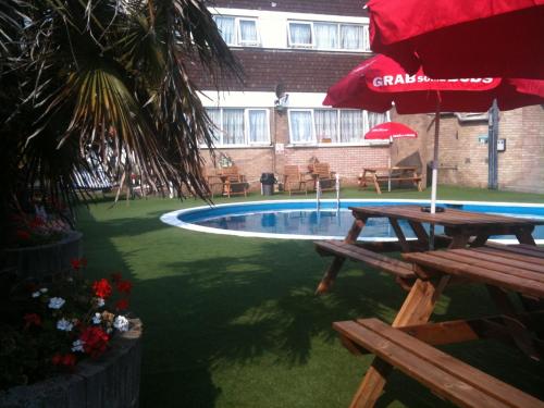 a swimming pool with two picnic tables and a red umbrella at Hotel Victoria in Great Yarmouth
