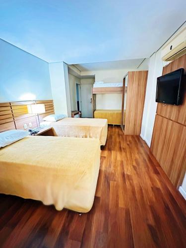 a hotel room with two beds and a flat screen tv at Umbu Hotel Porto Alegre - Centro Histórico - Prox Aeroporto in Porto Alegre