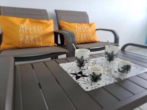 a table with two chairs and two cups on it at Ste Luce, N° 11 Appart -300m Plage de Mabouyas in Corps de Garde