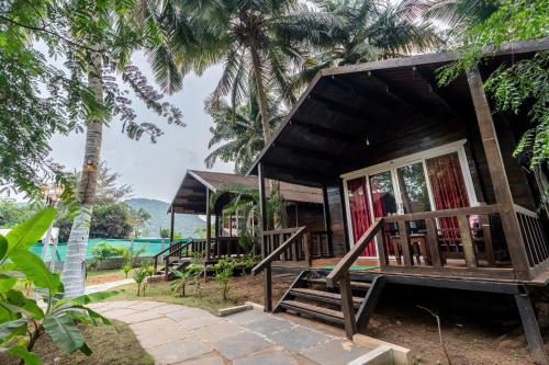 a small house with a porch and palm trees at The Exotica Agonda in Agonda
