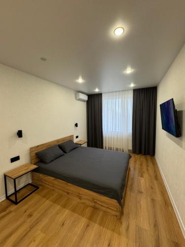 een slaapkamer met een bed en een houten vloer bij Люкс Апартаменты White Pearl на Подолье in Vinnytsya