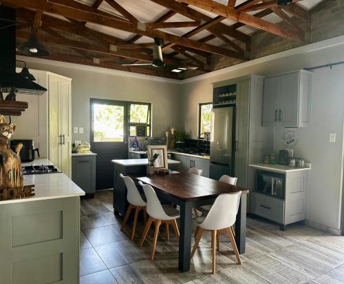 a kitchen with a wooden table and white chairs at Palm Tree Cottage Felixton in Richards Bay
