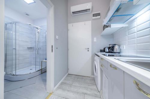 uma casa de banho branca com um chuveiro e um lavatório. em JS Modern Downtown Studios-Self Check-in em Budapeste