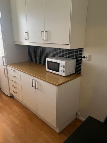 a kitchen with white cabinets and a microwave on a counter at Apartment in Gothenburg in Gothenburg