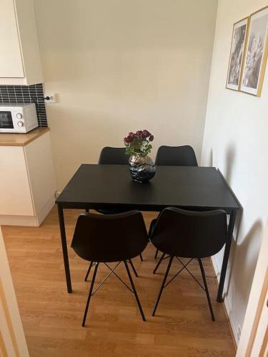 una mesa negra con 4 sillas y un jarrón con flores en Apartment in Gothenburg en Gotemburgo