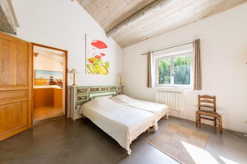 a bedroom with a bed and a window and a chair at Mas Titourin - Moulin du 18ème entièrement rénové in Ansouis