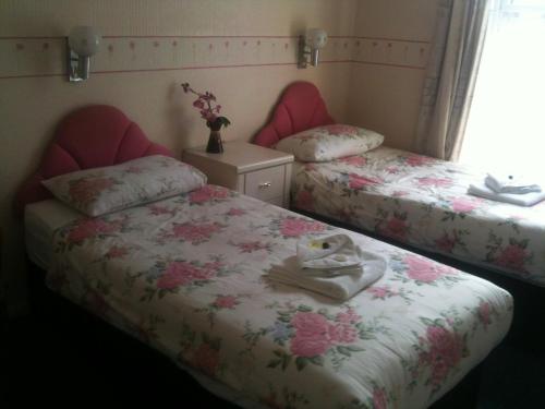 a bedroom with two beds with pink flowers on them at Hotel Victoria in Great Yarmouth