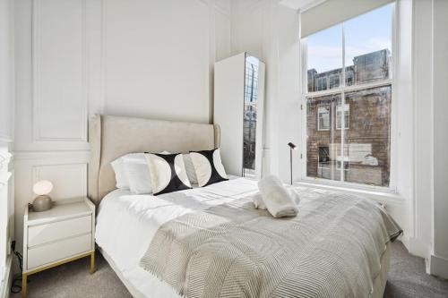 a white bedroom with a large bed and a window at (G2) Central 1 Bed Blythswood Flat in Glasgow