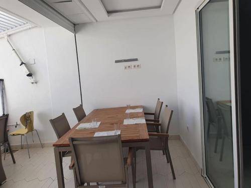 a dining room with a wooden table and chairs at bel appartement vue sur mer in Nabeul