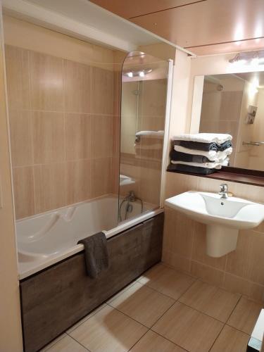 uma casa de banho com uma banheira, um lavatório e um espelho. em Le Croisic Face Mer em Le Croisic