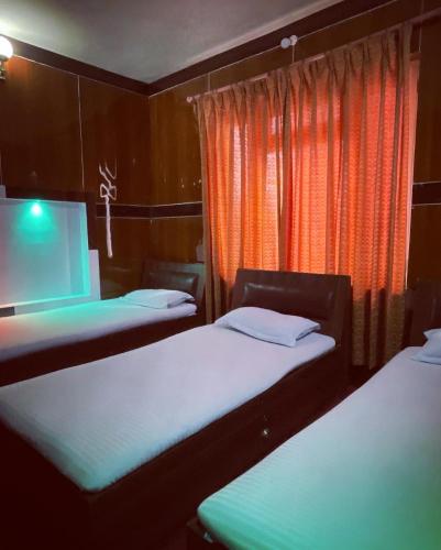 two beds in a room with an orange curtain at Sudha’s Garden Home in Kathmandu