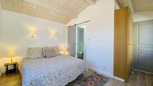 ル・ボワ・プラージュ・アン・レにあるSuperbe villa entièrement équipée avec piscineのベッドルーム1室(ベッド1台、ランプ2つ、ドア付)