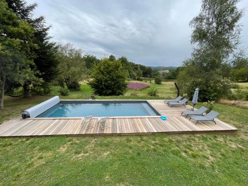 une piscine avec deux chaises et une terrasse en bois dans l'établissement Une pause en Corrèze, à Sarroux