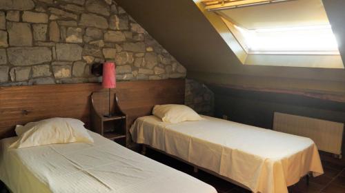 two beds in a room with a stone wall at Gîtes Ferme de la Barrière in Chimay