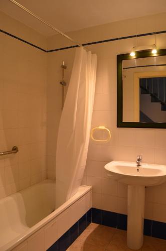 een badkamer met een bad, een wastafel en een bad tubermottermott bij augustha resort in Islantilla