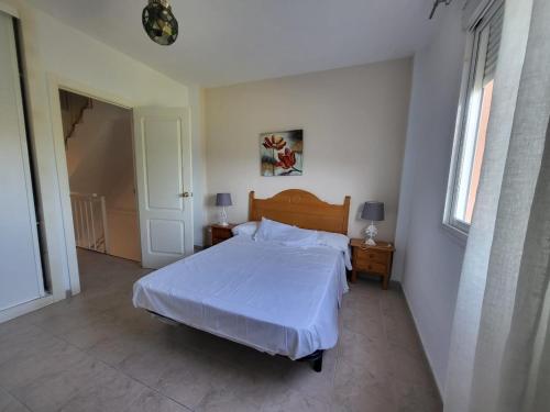 1 dormitorio con 1 cama con colcha blanca en augustha resort, en Islantilla