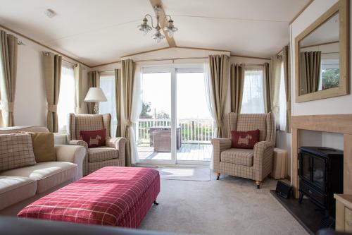 a living room with a couch and chairs and a fireplace at St Helens Coastal Resort in Saint Helens