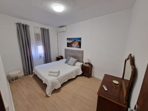 Schlafzimmer mit einem weißen Bett und Holzboden in der Unterkunft Casa Victoria in Bargas