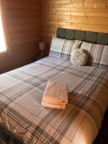 a bedroom with a bed with a checkered blanket at Log Cabin in the City with hot tub in Culloden