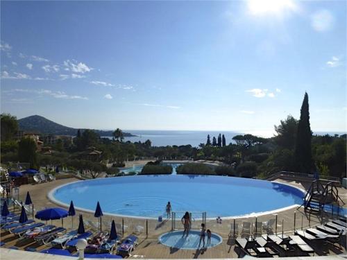 a large swimming pool with lounge chairs and the ocean at Studio 4P Vue Mer Calme Cap Esterel in Saint-Raphaël