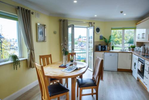 Il comprend une cuisine avec une table et des chaises en bois ainsi qu'une cuisine aux murs jaunes. dans l'établissement Waterfront Self Catering Houses, à Carrick-on-Shannon