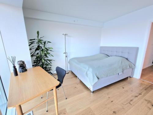 a bedroom with a bed and a wooden table at Tranquil apartment with panorama view over ocean above 20th floor in Aarhus
