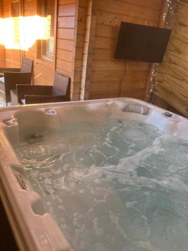 a jacuzzi tub in a room with a television at Log Cabin in the City with hot tub in Culloden