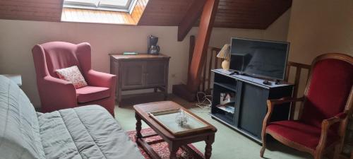 sala de estar con TV y 2 sillas en Location chambre dans villa, en Villers-Robert