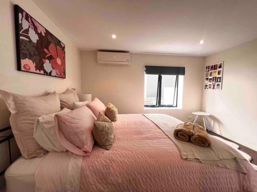1 dormitorio con 1 cama grande con almohadas rosas en Bulimba Guest House en Brisbane