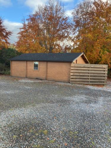 a wooden garage with a fence in a parking lot at Log Cabin in the City with hot tub in Culloden