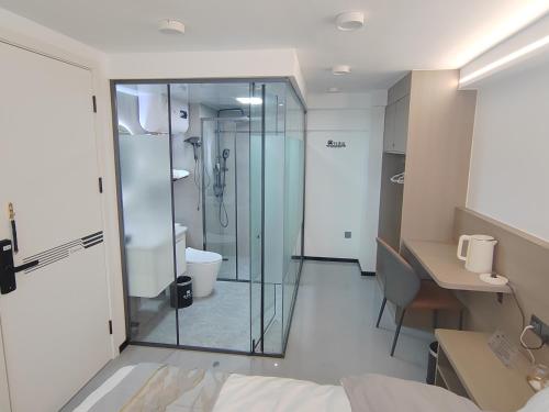 a bathroom with a glass shower and a desk at South Wind Blowing Dreams B&B - Xiamen North Railway Station in Xiamen