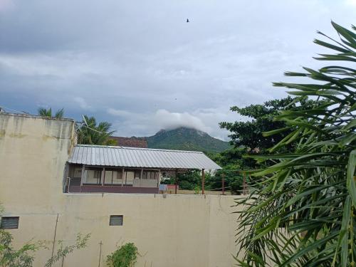 a building with a mountain in the background at Full Moon House Tiruvannamalai in Tiruvannāmalai