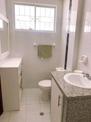 Baño blanco con aseo y lavamanos en Apartamento Loja Cómodo e Independiente, en Loja