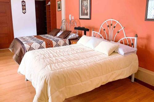 1 dormitorio con 2 camas y paredes de color naranja en Apartamento Loja Cómodo e Independiente, en Loja