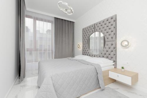 - une chambre blanche avec un lit et un miroir dans l'établissement Warsaw Sarmacka Apartment with Gym, Sauna and Parking by Renters, à Varsovie